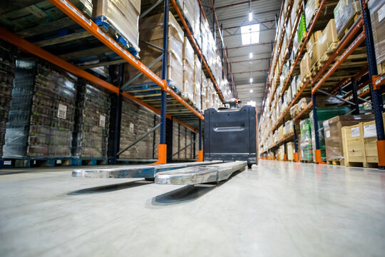Lift truck parked on alley between shelves in huge warehouse