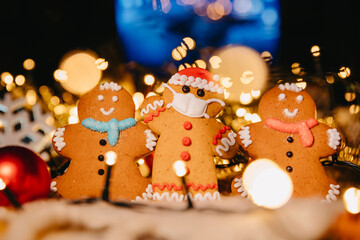 New Year and Christmas celebration in a coronavirus pandemic, conceptual background: Lots of ginger men with face mask on xmas background