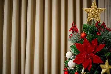 Detalhe de árvore de Natal com cortina ao fundo.
