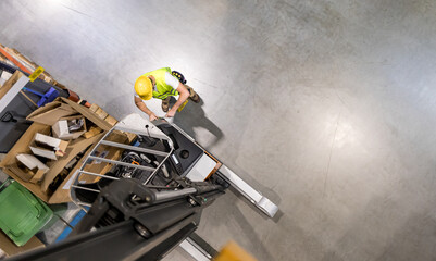 Mechanic repairs forklift in warehouse, view from above © leszekglasner