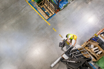 Mechanic repairs forklift in warehouse, view from above