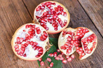 Pomegranate fruit and cut half ripe pomegranate with seeds on wooden table background