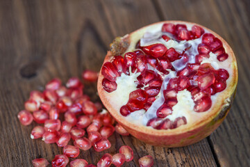 Pomegranate fruit and cut half ripe pomegranate with seeds on wooden table background.