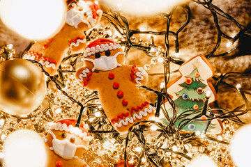 Special New Year's background with elements of the Christmas cookies, festive lights, Christmas ornaments: gingerbread in the shape of Santa Claus with a protective medical