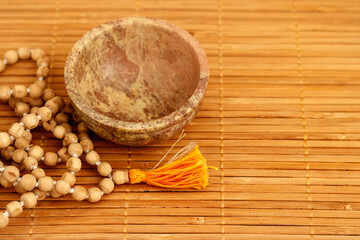 bowl with buddhist mala beads on wooden background with copy space. accessory for mindfulness or meditation. Close up, top view