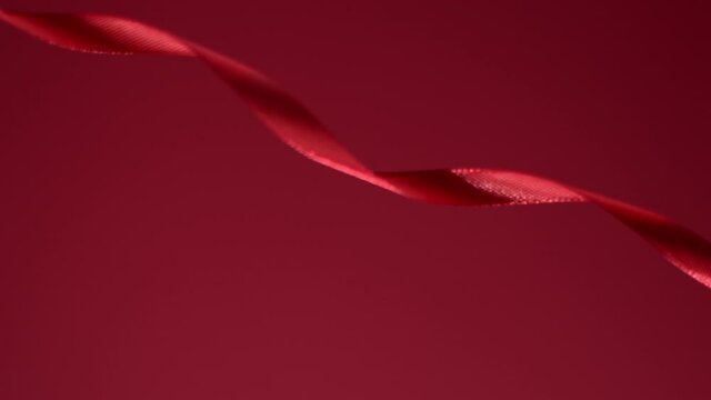 Deep red colored silky ribbon is moving on a velvety reddish red background. Atmospheric classy video background. New year, Christmas, St. Valentine festive mood. 4k still high quality footage