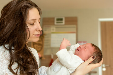 Obraz na płótnie Canvas Beautiful young mother holding her newborn baby boy after labor in hospital. Mother giving birth to child. Newborn baby in delivery room. Parent and infant first moments of bonding. Happy mother's day