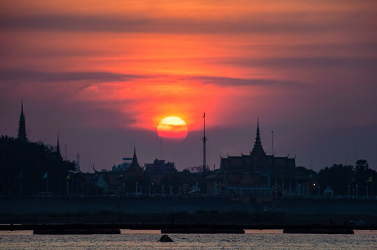 ROYAL PALACE, PHNOM PENH, CAMBODIA - 08 February 2009: Huge sun over Royal Palace and Phnom Penh city scape from boat on river.