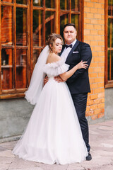 Fototapeta premium Wedding couple in stylish clothes with a beautiful bridal bouquet of delicate roses