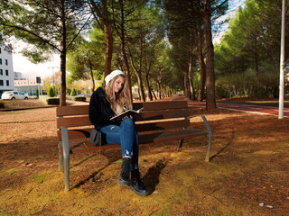 Young woman with cheerful fitness sitting on a bench reading a book