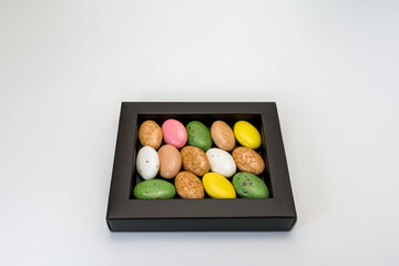 candy dragees in a multi-colored glaze in a box on a white background