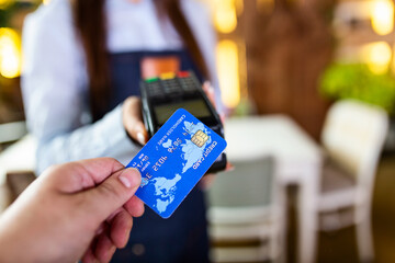 Contactless payment concept, female holding credit card near nfc technology on counter, client make transaction pay bill on terminal rfid cashier machine in restaurant store, close up view