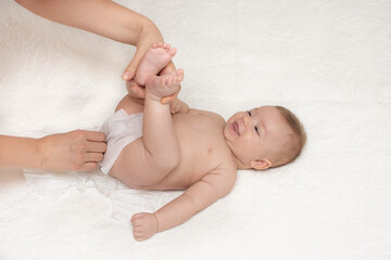 Close up of mother cleaning up baby by wet tissue when changing nappies or diaper in white nursery with bed. Hygiene concept.  Cleaning wipe, pure.