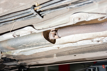 Rusty and old exhaust pipe under the car, bottom view.