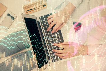 Double exposure of woman hands working on computer and forex graph hologram drawing. Top View. Financial analysis concept.