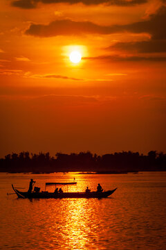 DOLPHIN WATCHING, MEKONG RIVER, KRATIE PROVINCE, CAMBODIA - 31 January 2012: Tourist on boat at sunset looking for the elusive irrawaddy dolphin.