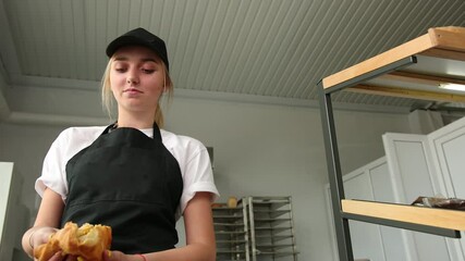 Female salesman divides cake of puff pastry with apple jam filling in half, demonstrating the quality food - Powered by Adobe