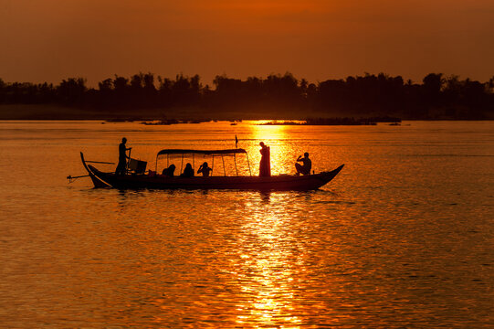 DOLPHIN WATCHING, MEKONG RIVER, KRATIE PROVINCE, CAMBODIA - 31 January 2012: Tourist on boat looking for the elusive irrawaddy dolphin photographs a beautiful sunset.