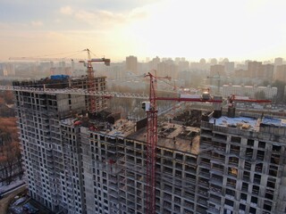 Aerial view construction of a modern office building. The work of building tower cranes against the background of the cityscape