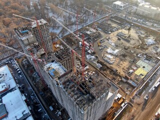 Aerial view construction of a modern office building. The work of building tower cranes against the background of the cityscape