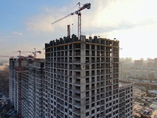 Aerial view construction of a modern office building. The work of building tower cranes against the background of the cityscape