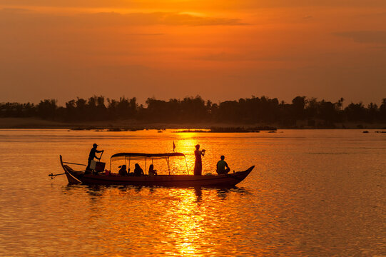 DOLPHIN WATCHING, MEKONG RIVER, KRATIE PROVINCE, CAMBODIA - 31 January 2012: Tourist on boat at sunset tries to photograph the elusive irrawaddy dolphin.