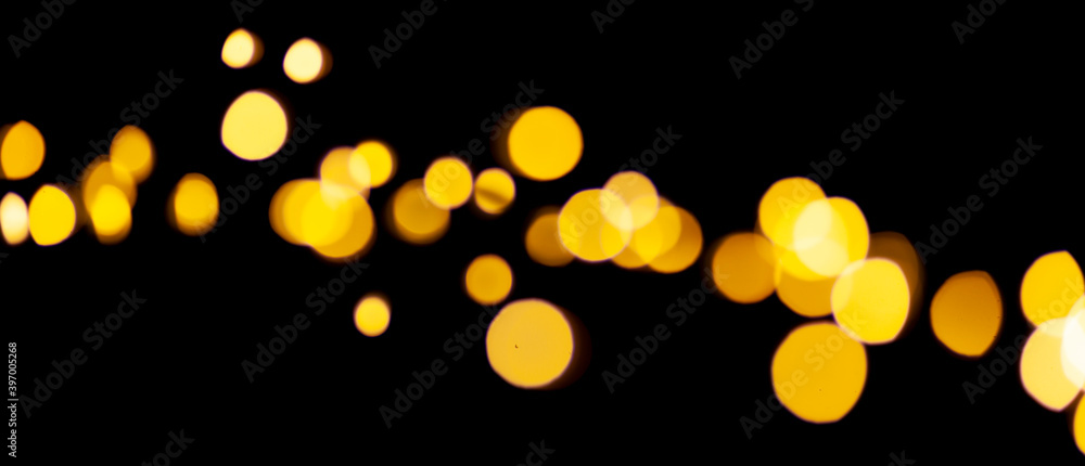 Poster Yellow bokeh lights on a black background. Abstract shiny pattern in defocus.