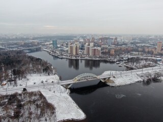 Aerial view panorama of the railway bridge across the river against the background of the city in winter. Travel by rail.