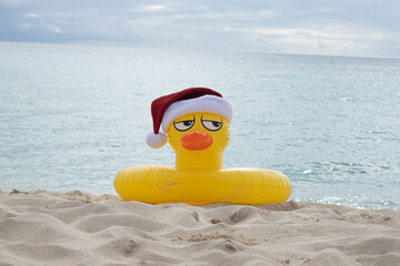 
YELLOW INFLATABLE LIFEGUARD DUCK WITH SANTA CLAUS HAT ON THE SHORES OF A CARIBBEAN BEACH ON A SUNNY DAY
