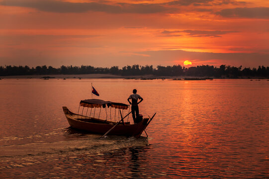 DOLPHIN WATCHING, MEKONG RIVER, KRATIE PROVINCE, CAMBODIA - 31 January 2012: Local dolphin watch boat opperator watches beautiful sunset at end of his day.