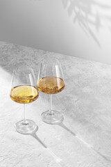 Two wine glasses stand against a white background and are illuminated by a bright hard light. Happy valentine's day greeting concept.