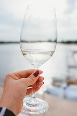 Woman's hand holding a glass with sparkling white wine. Yacht, wine, leisure, relaxing concept
