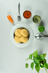 Homemade tasty rava idly in a plate along with chutney and curry