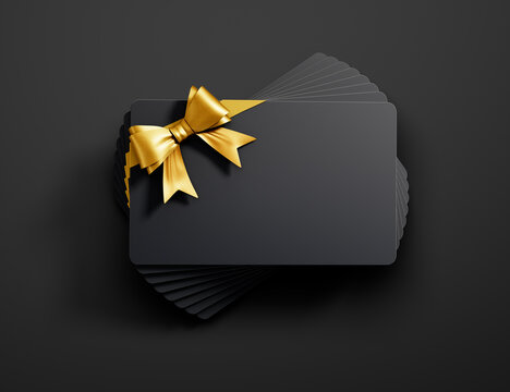 Stack of black credit or gift cards with golden ribbon isolated on dark background - 3D illustration