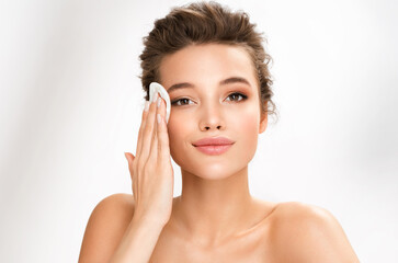 Woman removing makeup, holds cotton pads near face. Photo of woman with perfect skin on white...