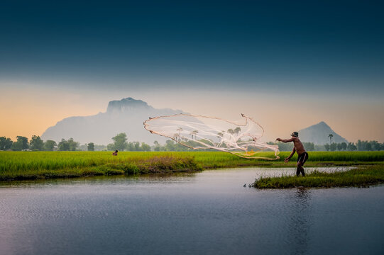 THROWING FISHING NET, KAMPOT, CAMBODIA - 14 October 2013: Cambodian fisherman fishes at the end of the day.