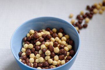 Bowl with chocolate and milk balls and a glass of milk on the table.