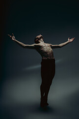 Inspiration. Young graceful male ballet dancer in minimal black style isolated on dark studio background. Art, motion, flexibility creation concept. Flexible caucasian ballet dancer. Copyspace for ad