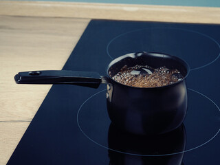 coffee is brewed in Cezve on a modern induction cooker.