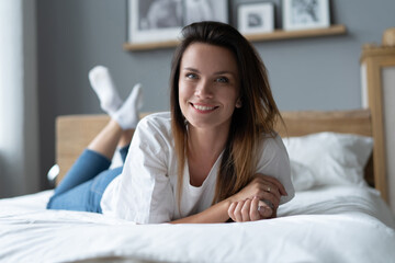 Obraz na płótnie Canvas Portrait of a smiling pretty young woman lying in bed.