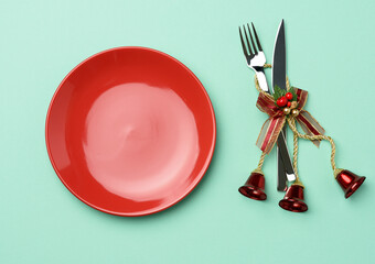 empty round red ceramic plate, knife and fork on green background