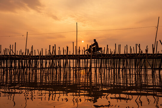 Motorbike at sunset, Ko Paen Bamboo bridge, Kompong Cham, Cambodia. This temporary bamboo bridge is reconstructed every year to span a contributory to the Mekong from main city to an island.
