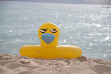 
YELLOW INFLATABLE LIFEGUARD DUCK WITH MOUTH COVER ON THE SHORE OF THE BEACH ON A SUNNY DAY