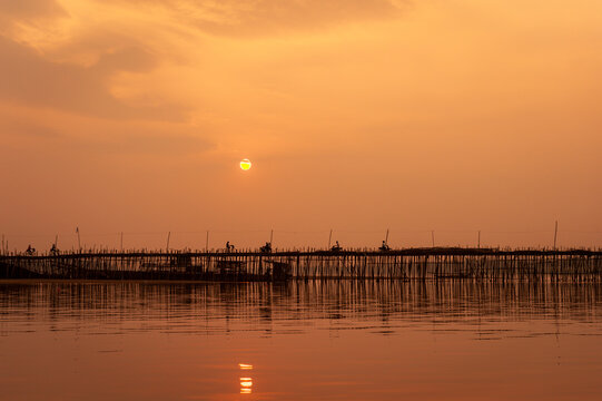 Traffic at sunset, Ko Paen Bamboo bridge, Kompong Cham, Cambodia. This temporary bamboo bridge is reconstructed every year to span a contributoryto the Mekong from main city to an island.