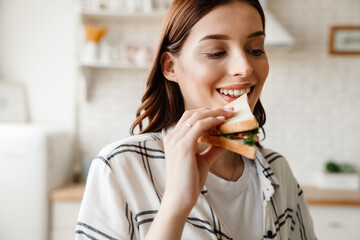 Beautiful happy woman smiling while eating sandwich