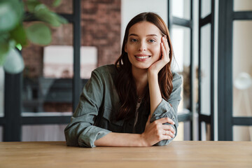 Beautiful happy nice woman smiling at camera while sitting at table
