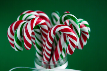 Candy canes close up. Christmas background. Green and red sweet sticks in the glass jar with white ribbon. Poster, banner, greeting card template. Festive backdrop. Holiday season - Powered by Adobe