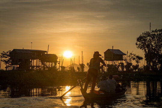 FLOATING VILLAGE, KOMPONG CHNANG, CAMBODIA - 15 December 2014: Tourists on small traditional fishing boat take photos at sunset.