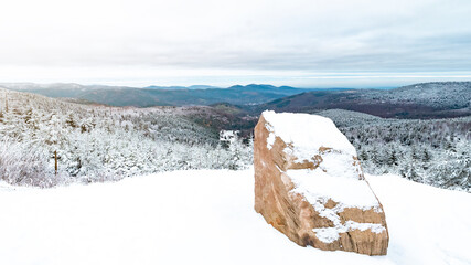 Stunning view panorama of snowy frozen mountain landscape in winter in Black Forest - winter wonderland / Snowscape background with a snowy rock in the front