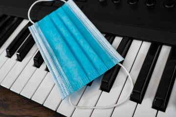 Piano and medical mask in music studio. Covid-19 restrictions concept.